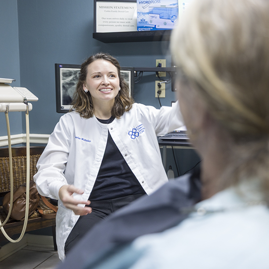 Doctor Whitaker talking with a patient in the treatment chair