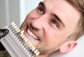 Man's smile compared with tooth color chart