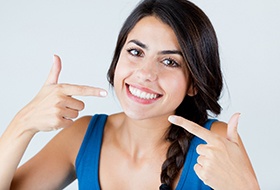 woman smiling and pointing to her teeth 