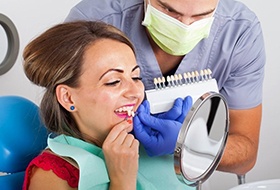 woman in red shirt trying on porcelain veneers in dental chair 