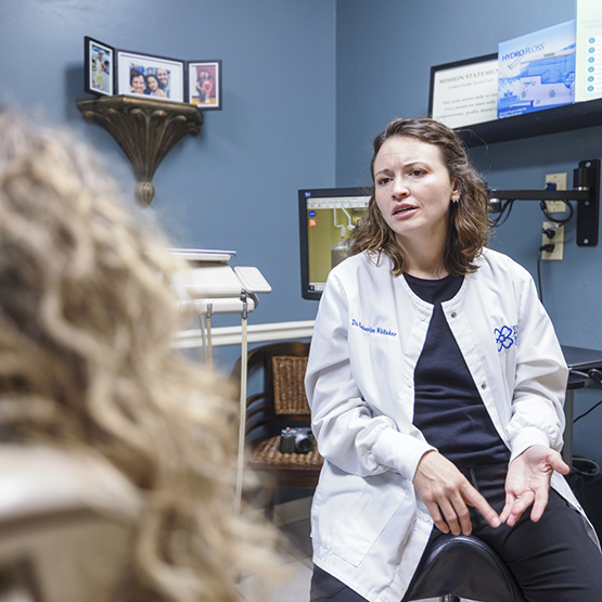 Doctor Whitaker talking with a patient in the treatment chair