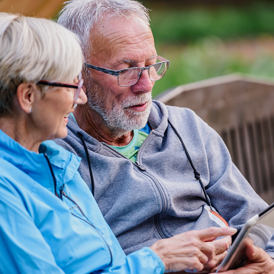 Senior couple on a bench looking at a phone