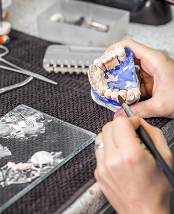 Dental lab worker painting a denture