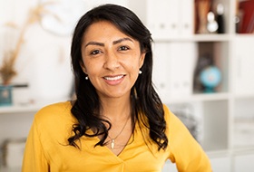 a person smiling and standing in front of a bookshelf