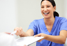 dental assistant smiling while handing patient form