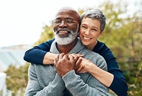 Senior couple hugging outside and smiling