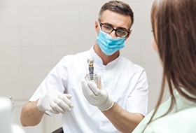 Corbin dentist holding model dental implant for patient