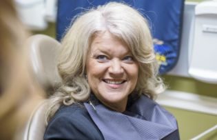 Smiling woman in the dental chair with curly blonde hair