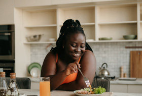Woman smiling while eating healthy meal at home