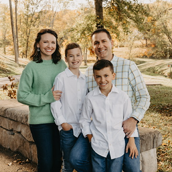 Doctor Whitaker smiling in the woods with her husband and two sons