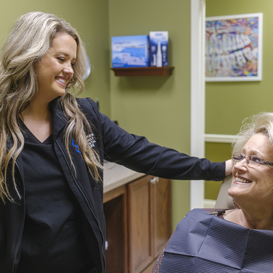 Smiling dental team member putting her hand on a patient's shoulder