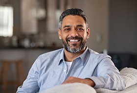 Smiling man sitting on couch while resting arm