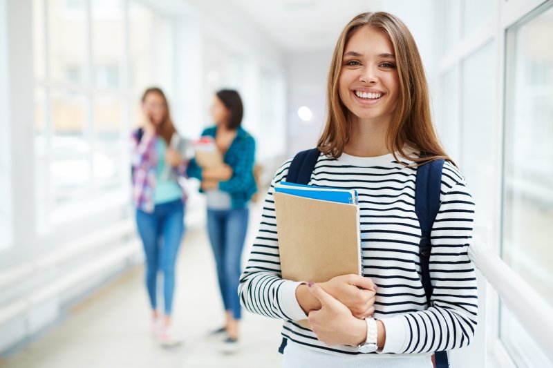 young woman in school hallway holding books