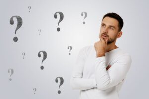Man wearing thoughtful expression while question marks float around him 